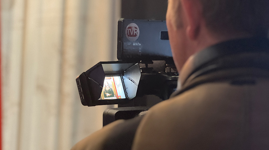 journaliste (TVR) avec sa caméra, filmant dans une exposition