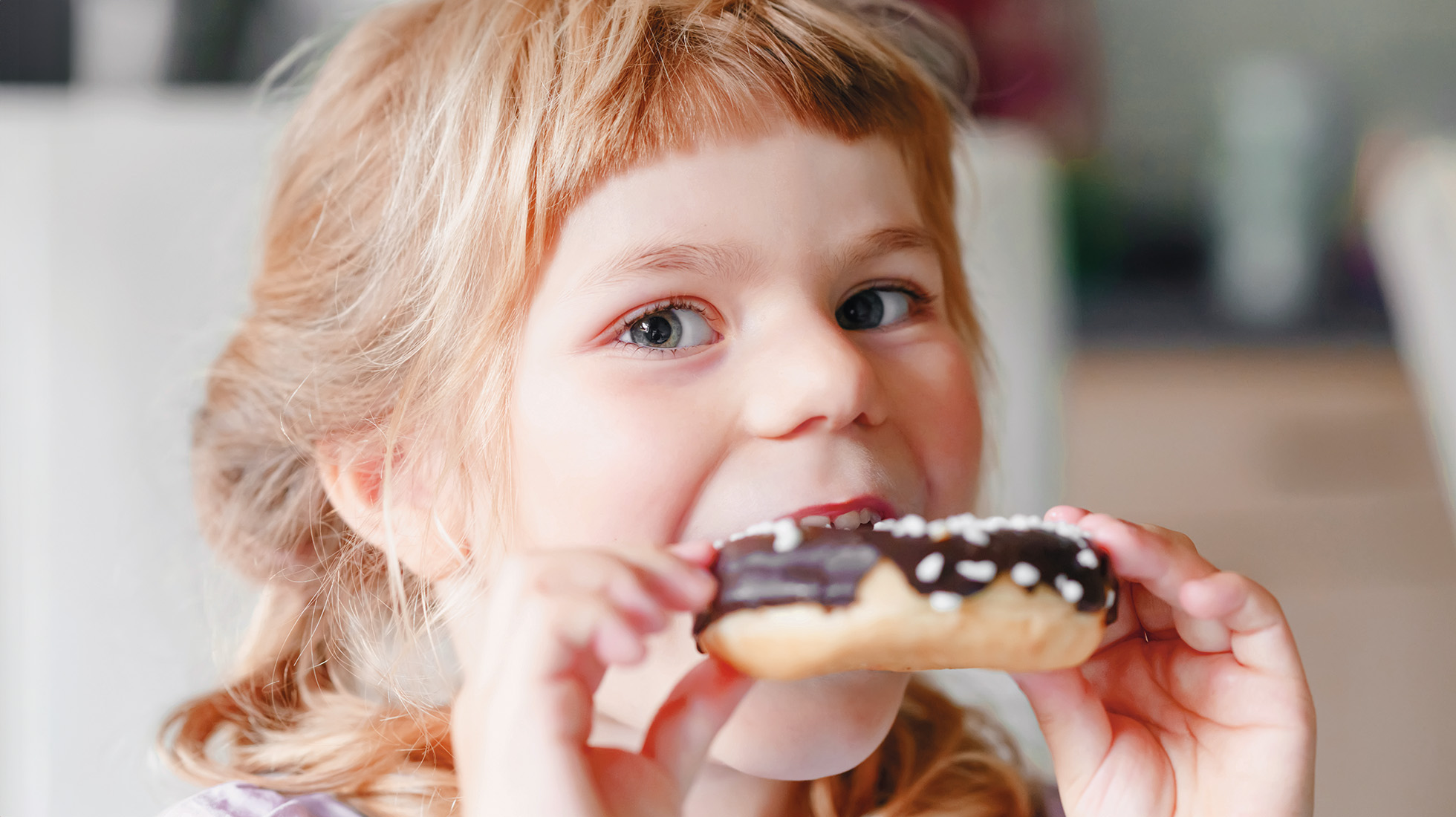 petite fille qui croque un beignet