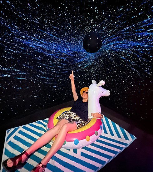 Anaïs, médiatrice conférencière au Planétarium, sur une bouée gonflable, sous un trou noir et les étoiles